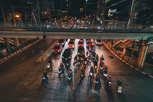 泰国曼谷夜晚街道拥挤的车流和等待过十字路口的摩托车