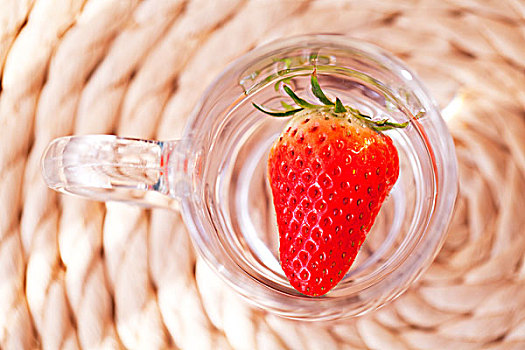红色新鲜的草莓泡在水杯中的特写