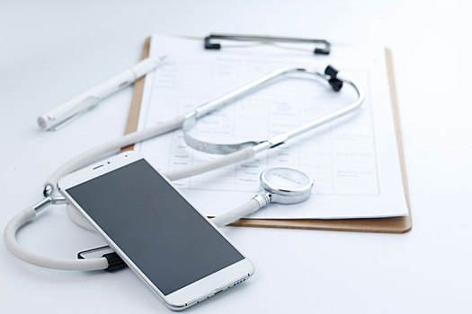 手机,听诊器和病历夹放在白色桌面上