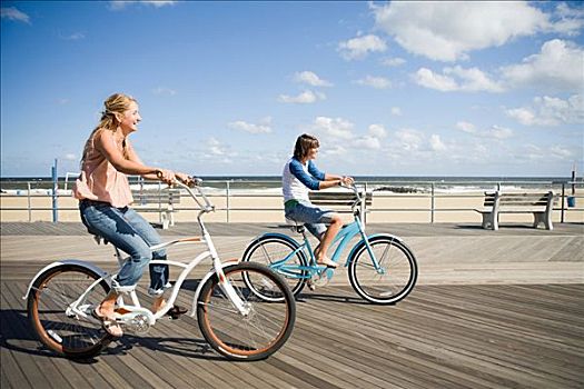 两个女人,骑自行车,木板路