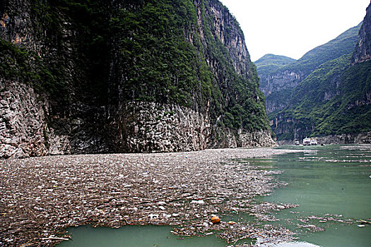 2011年8月7日,前几天三峡库区下大雨产生大量的生活垃圾呈漂浮物堆积在小三峡巴雾峡上游峡谷口,严重影响航道安全,一只小船正忙着打捞这些漂浮物显得力不从心,旅游船只能从漂浮物堆积薄一些的河面上通过