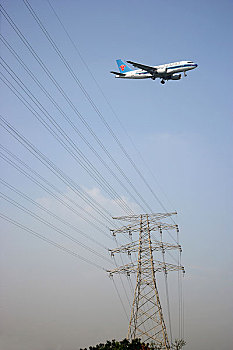 从高压线电塔上空飞过的客机