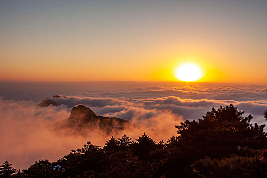 中国安徽黄山风景区,冬日雪后放晴,夕阳映照山崖云雾飘渺宛若仙境
