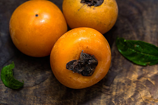 成熟的香蜜甜柿子摆放在陈旧的木板上