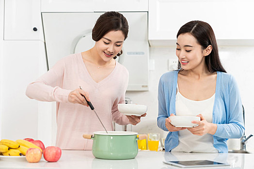 年轻女子在厨房边做饭边和朋友聊天