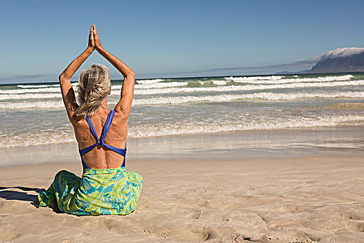 后视图,女人,抬臂,实践,瑜珈,坐,岸边,海滩