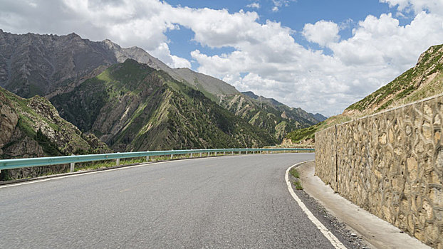 中国新疆夏季蓝天白云下高山草原g217独库公路弯道特写