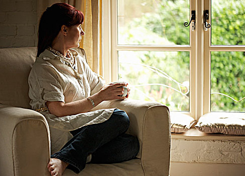 坐,女人,扶手椅,拿着,咖啡杯,望向窗外