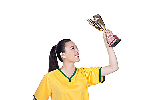 一个穿足球队服拿着奖杯的女青年