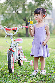 站在自行车旁吃雪糕的小女孩