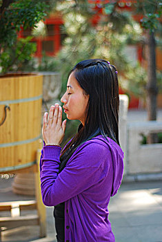 一名年轻女性跪在寺庙中祈祷