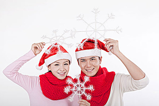 戴着圣诞帽的青年伴侣拿着雪花