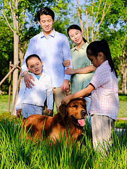 快乐的四口之家和宠物狗在公园玩耍