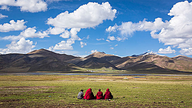 坐在草地眺望远山的僧侣们