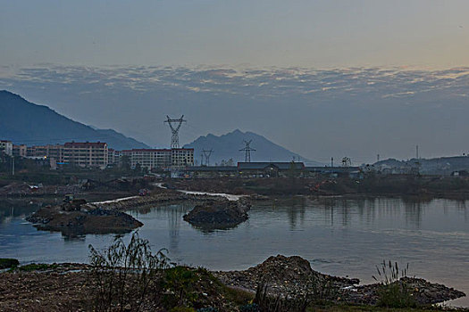 输电塔,房屋,炊烟,截流,拖拉机,汽车,推土机,池塘,河流,两岸,高压线,高压塔,电力,黄昏,清洁能源,绿色电力