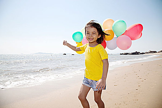小女孩手拿气球在沙滩玩耍