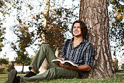 男青年,坐,树,拿着,书本,看别处,微笑