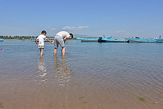 海边父子玩水捡贝壳玩水的快乐少年