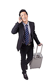 一个拿行李箱打电话的青年商务男士