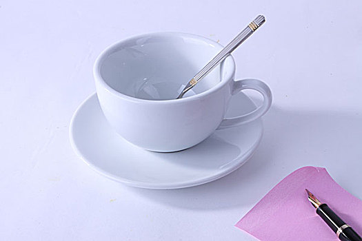一个空的咖啡杯和纸张钢笔