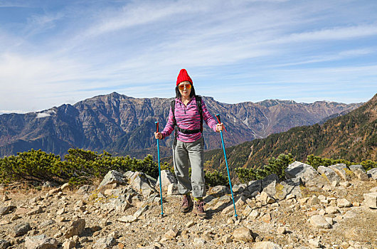 一个手拿登山杖站在山顶看着远方风景的女性徒步旅行者
