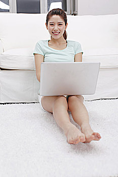 年轻女士坐在沙发旁使用电脑