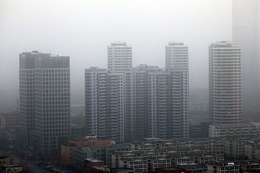 山东省日照市,大雾沙尘冷空气接连来袭,远处城市建筑灰蒙蒙一片