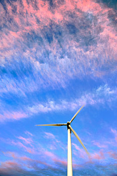 夏季里在落日彩霞中转动的风车风轮