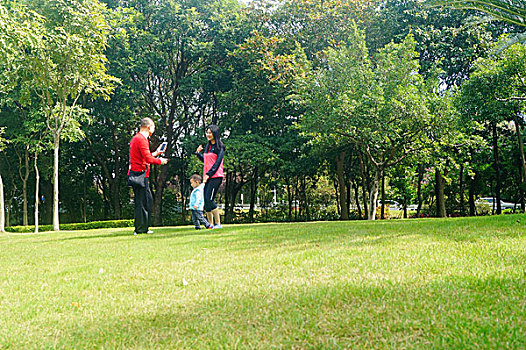 年轻夫妇带着孩子在公园草坪上拍照