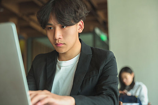 一名亚洲男子使用笔记本电脑加班