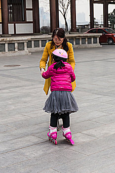 妈妈在帮助女儿学习轮滑并扶着她