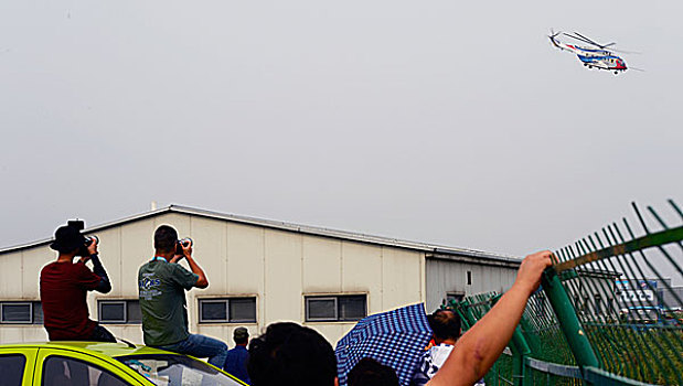 坐在车顶拍摄天津直博会上的ac313的观众