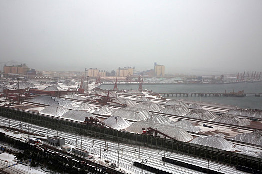 山东省日照市,狂风暴雪席卷港城,港口生产受阻,红色矿石堆场变身,雪山