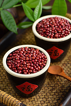 复古中国风格背景上放在两个福字水缸里的红小豆特写图片