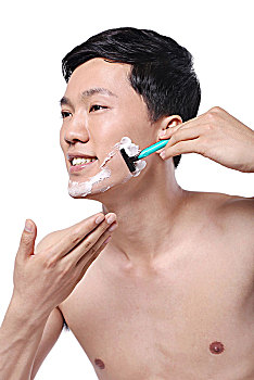 白色背景下面容清爽手拿剃须刀的亚洲男青年