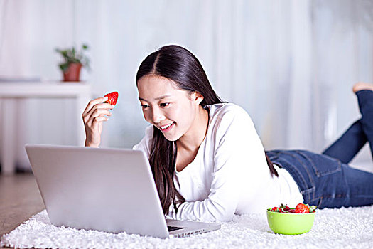 休闲女士在电脑前吃草莓
