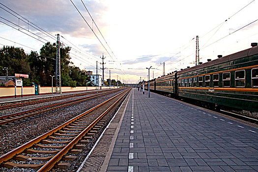 空旷的火车站台和延伸的铁轨和绿皮火车