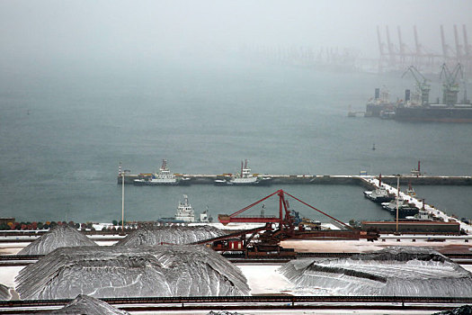 山东省日照市,狂风暴雪席卷港城,港口生产受阻,红色矿石堆场变身,雪山