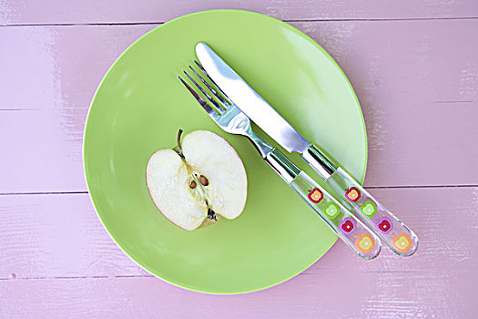 盘子,绿色,苹果,一半,银器,静物,食物,概念,桌子,粉色,半个苹果,核,刀,叉子,塑料制品,图案,水果,餐食,新鲜,健康,维生素,营养,饮食