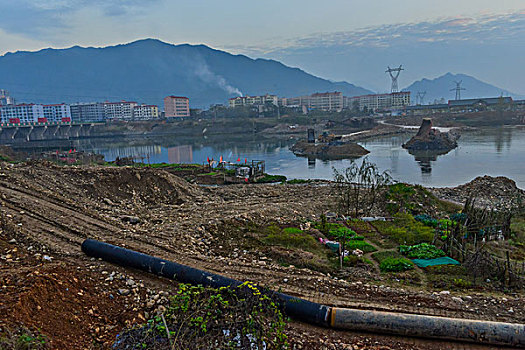 管道,房屋,炊烟,截流,拖拉机,汽车,推土机,池塘,河流,两岸,高压线,高压塔,电力,黄昏,清洁能源,绿色电力