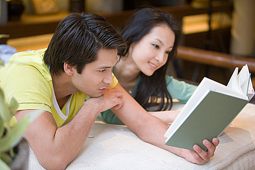 一对年轻夫妇趴在床上看书