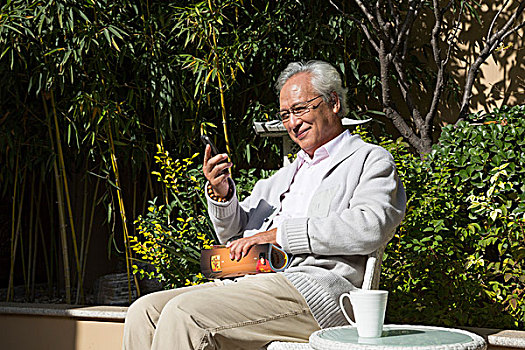 老男人在花园里看书打电话