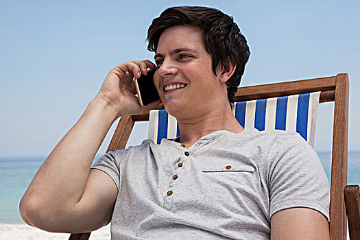 男人,坐,太阳椅,交谈,手机,海滩,微笑