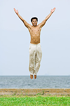 男人,跳跃,空中,抬臂,看镜头,微笑,海洋,背景