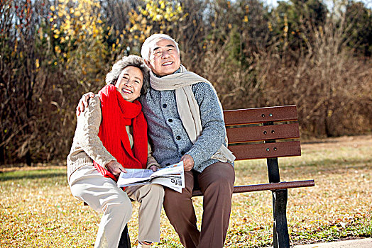 坐在椅子上拿報紙的老夫妻