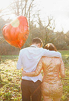 夫妇在公园,控股心,形,气球,背视图