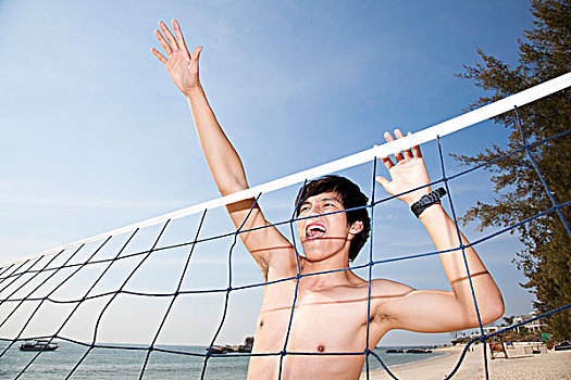 年轻男人在海边玩沙滩排球