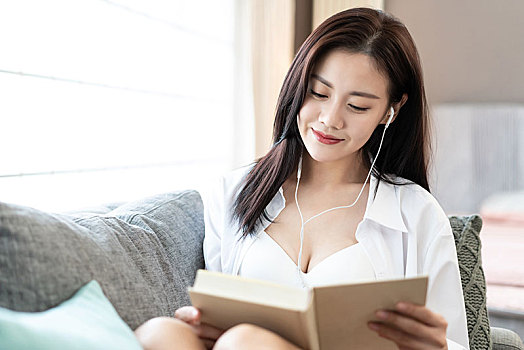 年輕女子在沙發上看書聽音樂