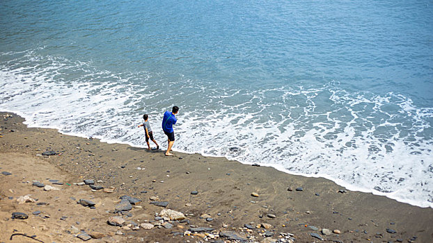 一对父子在渔港附近的海滩嬉戏