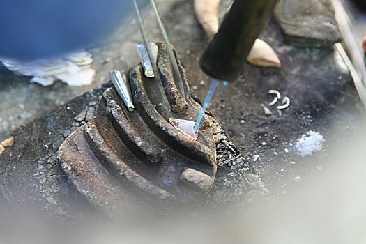 格尔木市区一个用传统方法打制银器的商贩在打制银器